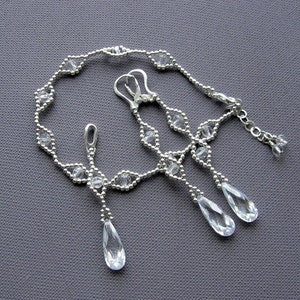 Puede incluir: Un collar y pendientes de plata con cuentas de cristal transparente y colgantes en forma de l&aacute;grima.