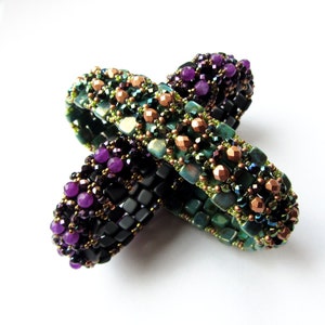 May include: Two beaded bracelets, one with black, green, and purple beads, and the other with green, copper, and purple beads.