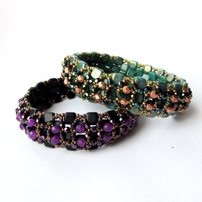 May include: Two beaded bracelets, one with purple and black beads and the other with green, copper, and black beads.