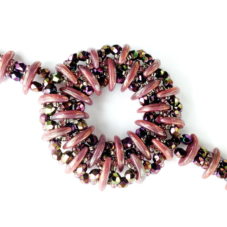 May include: A close-up of a purple and iridescent beaded bracelet with a circular design. The beads are arranged in a spiral pattern, creating a unique and eye-catching look.
