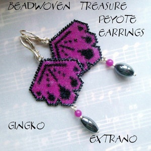 May include: A pair of purple and black beaded earrings with silver hooks and black hematite dangles. The earrings are labelled "Beadwoven Treasure Peyote Earrings Ginkgo Extrano".