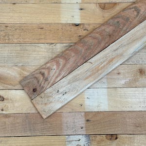 May include: A close-up of a wooden surface made of several planks of wood. The planks are arranged in a horizontal pattern and are of varying shades of brown. A single plank of wood is placed diagonally across the surface, creating a visual contrast.