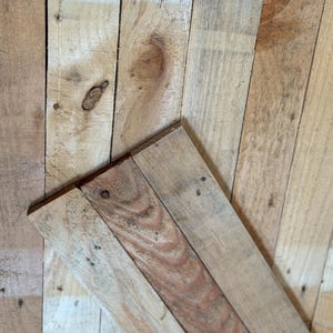 May include: A close-up of a wooden surface made of multiple planks of wood. The wood is a light brown colour and has a natural, rustic look.