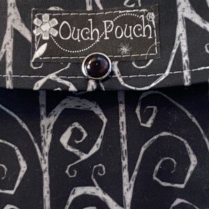 May include: Black fabric pouch with a white swirl pattern and a black label that says "Ouch Pouch".