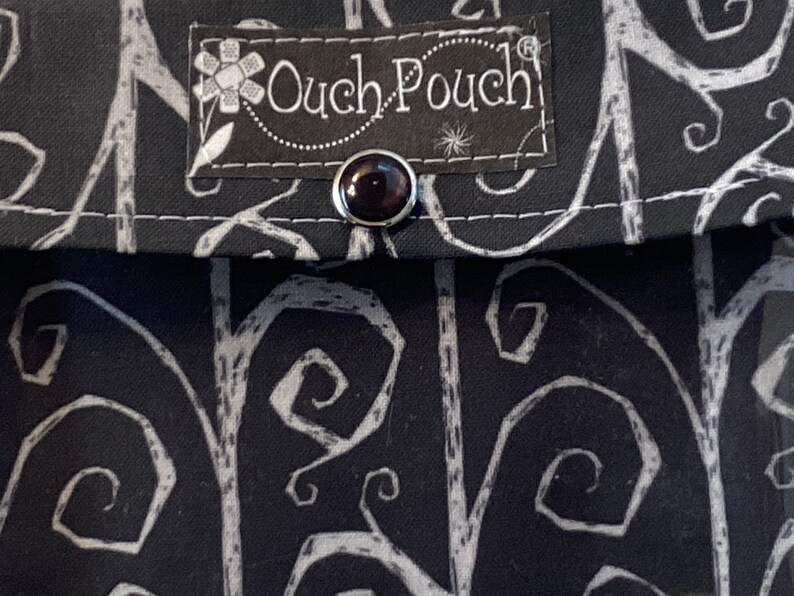 May include: Black fabric pouch with a white swirl pattern and a black label that says "Ouch Pouch".
