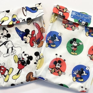 Könnte beinhalten: Zwei transparente Beutel mit weißem Stoff mit Mickey Mouse in verschiedenen Posen. Ein Beutel hat Mickey Mouse-Illustrationen, der andere hat Mickey Mouse in bunten Kreisen. Jeder Beutel hat einen blauen Knopfverschluss.