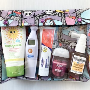 May include: A clear zippered pouch with a colorful Nightmare Before Christmas print. The pouch contains a variety of items, including sunscreen, a thermometer, hand sanitizer, a tube of cream, and a nasal spray.