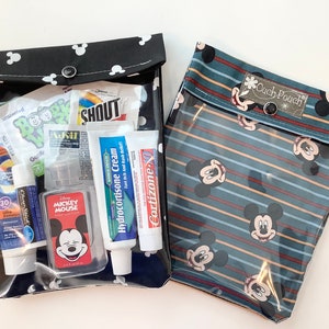 May include: Two clear plastic zippered pouches with Mickey Mouse patterns. The black pouch has white polka dots and contains various toiletries, including sunscreen, hand sanitizer, and lip balm. The blue pouch has red and white stripes and the text "Ouch Pouch".