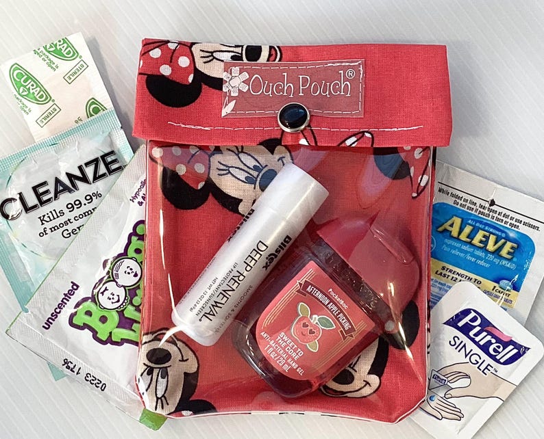 May include: A red and white Mickey Mouse themed pouch with a clear plastic window. The pouch contains a variety of items, including hand sanitizer, lip balm, and a small bottle of hand lotion. The pouch has a button closure and the text "Ouch Pouch" is printed on the front.