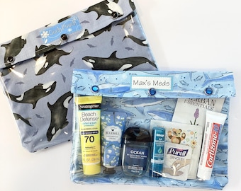 May include: Two clear, zippered pouches. One is closed, with a blue and white orca pattern. The other is open, with the text "Max's Meds" and contains sunscreen, hand cream, hand sanitizer, lip balm, and other essentials.