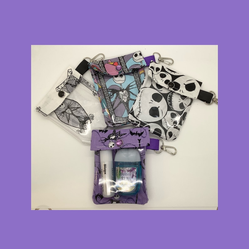 May include: Four clear plastic zippered pouches with different Nightmare Before Christmas character prints. The pouches have purple trim and a purple button closure. One pouch contains a small bottle of hand sanitizer and a lip balm.