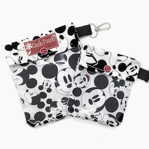 Könnte beinhalten: Zwei transparente Beutel mit einem schwarz-weißen Mickey Mouse-Muster. Jeder Beutel hat einen schwarzen Riemen mit einem silbernen Verschluss. Die obere Klappe jedes Beutels hat einen roten Knopf und den Text "Ouch Pouch".