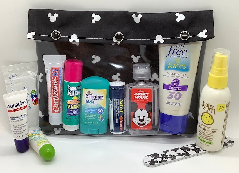 May include: A black and white Mickey Mouse themed travel bag with a clear zippered pouch containing various travel-sized toiletries, including sunscreen, hand sanitizer, lip balm, and a nail file.