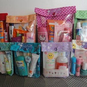 May include: Seven colorful zippered pouches with clear vinyl windows, each filled with various travel-sized toiletries and personal care items. The pouches are decorated with different patterns and designs.