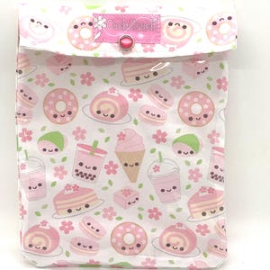 May include: A white pouch with a flap closure, adorned with a repeating pattern of pink donuts, cakes, macarons, and bubble tea. The design includes smiling faces and cherry blossoms. The flap has a pink button closure and a label that reads "Cutch Pouch".