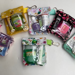 Puede incluir: Siete pequeñas bolsas transparentes con cremallera con exteriores de tela de varios colores y llaveros. Cada bolsa contiene pequeñas botellas de desinfectante de manos, bálsamo labial y otros artículos de tocador.