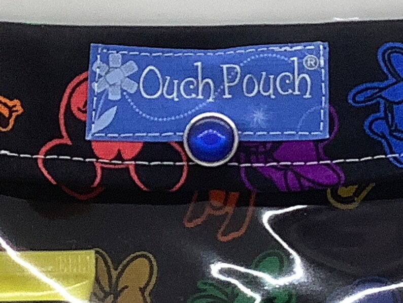 May include: A black fabric pouch with a blue label that says "Ouch Pouch" and a blue button. The pouch has a colorful pattern of cartoon characters.