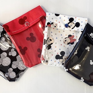 May include: Four fabric pouches with clear plastic windows. Each pouch has a black button closure and a different Mickey Mouse themed print. The prints include black and white Mickey Mouse heads, red Mickey Mouse heads, and a white background with colourful Mickey Mouse characters.