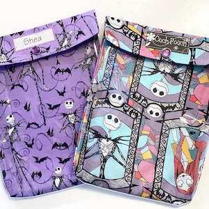 Könnte beinhalten: Zwei durchsichtige Plastik-Reißverschlusstaschen mit einem Nightmare Before Christmas-Motiv. Eine Tasche hat einen violetten Hintergrund mit einem sich wiederholenden schwarz-weißen Muster von Jack Skellington und Fledermäusen. Die andere Tasche hat ein blaues, rosa und gelbes Buntglasmuster mit Jack Skellington und Sally. Beide Taschen haben den Text "Ouch Pouch" auf der Vorderseite.