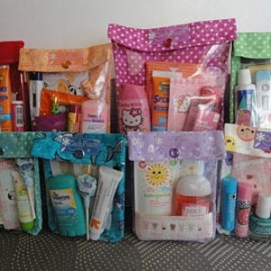 Puede incluir: Siete bolsas de tela coloridas con ventanas de pl&aacute;stico transparente, cada una llena de diversos art&iacute;culos de tocador y de cuidado personal de viaje. Las bolsas est&aacute;n decoradas con diferentes patrones y tienen un cierre de bot&oacute;n.