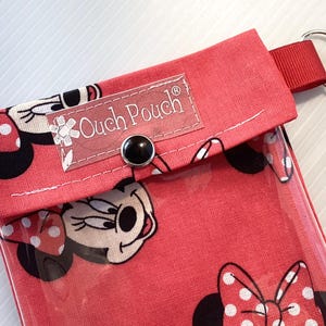 May include: Red fabric pouch with a clear plastic window, featuring a Mickey Mouse character design. The pouch has a snap closure and a label that reads "Ouch Pouch".