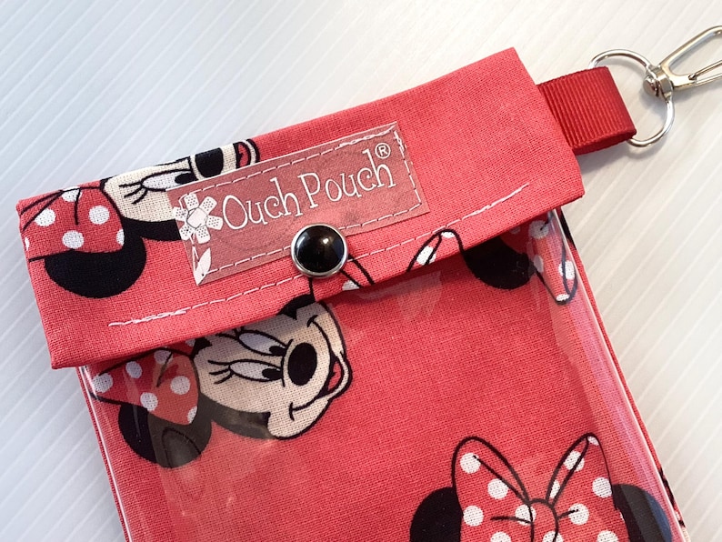 May include: Red fabric pouch with a clear plastic window, featuring a Mickey Mouse character design. The pouch has a snap closure and a label that reads "Ouch Pouch".