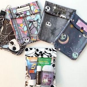 Puede incluir: Cuatro bolsas transparentes con cremallera de pl&aacute;stico con diferentes patrones coloridos que presentan al personaje Jack Skellington de la pel&iacute;cula Pesadilla antes de Navidad. Las bolsas est&aacute;n etiquetadas como "Disney Dream" y "Ouch Pouch". Una bolsa contiene una peque&ntilde;a botella de desinfectante para manos, un tubo de protector solar y un tubo de b&aacute;lsamo labial.