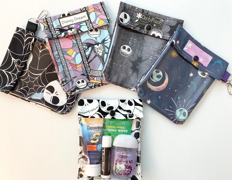 Puede incluir: Cuatro bolsas transparentes con cremallera de pl&aacute;stico con diferentes patrones coloridos que presentan al personaje Jack Skellington de la pel&iacute;cula Pesadilla antes de Navidad. Las bolsas est&aacute;n etiquetadas como "Disney Dream" y "Ouch Pouch". Una bolsa contiene una peque&ntilde;a botella de desinfectante para manos, un tubo de protector solar y un tubo de b&aacute;lsamo labial.
