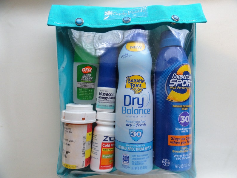 May include: A clear pouch with a teal top, containing various health and personal care items. Includes sunscreen, insect repellent, allergy medication, and cold relief medicine. The pouch is approximately 8 inches wide.
