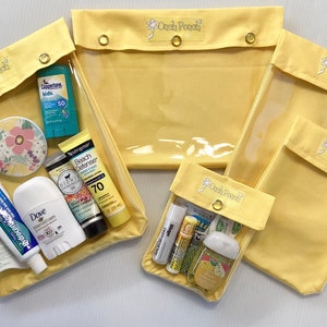 May include: Yellow Ooch Pouch bags in various sizes, some filled with toiletries. The bags have a clear front and a yellow fabric top with a snap closure. The text "Ooch Pouch" is printed on the top of each bag.