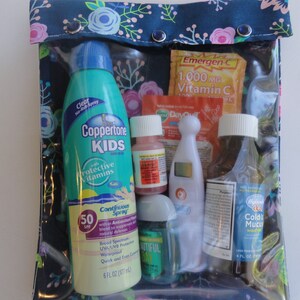 May include: A clear, zippered pouch with a floral patterned top, containing various health and wellness items. Includes a Coppertone Kids sunscreen bottle, Emergen-C packets, medicine bottles, a thermometer, and hand sanitizer. The sunscreen is 6 fl oz.