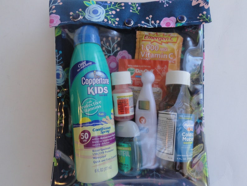 May include: A clear, zippered pouch with a floral patterned top, containing various health and wellness items. Includes a Coppertone Kids sunscreen bottle, Emergen-C packets, medicine bottles, a thermometer, and hand sanitizer. The sunscreen is 6 fl oz.