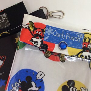 K&ouml;nnte beinhalten: Zwei Mickey Mouse-Themen-Schmerz-Taschen mit durchsichtigen Plastik-Vordertaschen. Die Tasche links ist schwarz mit einem roten Knopf und die Tasche rechts ist wei&szlig; mit einem blauen Knopf und einem roten, gelben und blauen Mickey Mouse-Druck.