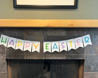 May include: A white banner with the words "HAPPY EASTER" in colorful letters. The banner is strung across a fireplace, with each letter in a different color: green, purple, yellow, pink, blue, and purple.