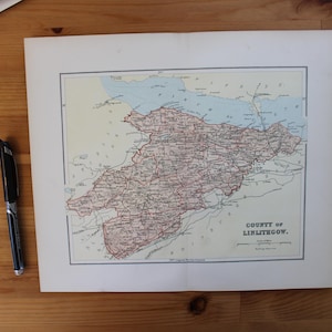 Może przedstawiać: Zabytkowa mapa hrabstwa Linlithgow, z szczegółowymi czerwonymi i czarnymi liniami przedstawiającymi drogi i granice. Mapa znajduje się na kremowym tle, z niebieskim reprezentującym zbiorniki wodne. Czarny długopis spoczywa na drewnianej powierzchni.