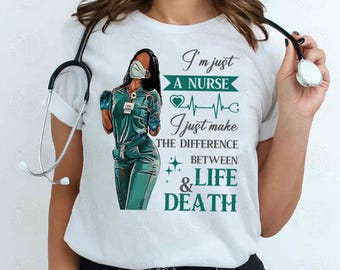 May include: A white t-shirt with a graphic of a Black woman wearing a surgical mask and scrubs. The text reads "I'm just a nurse I just make the difference between life & death".