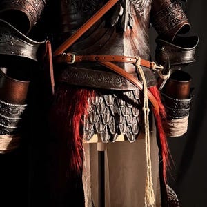 May include: Close-up of a detailed, dark brown and black medieval armor set. The armor features intricate embossed designs, leather straps, and a red fur-like accent. The image includes the text "Chloestore3".