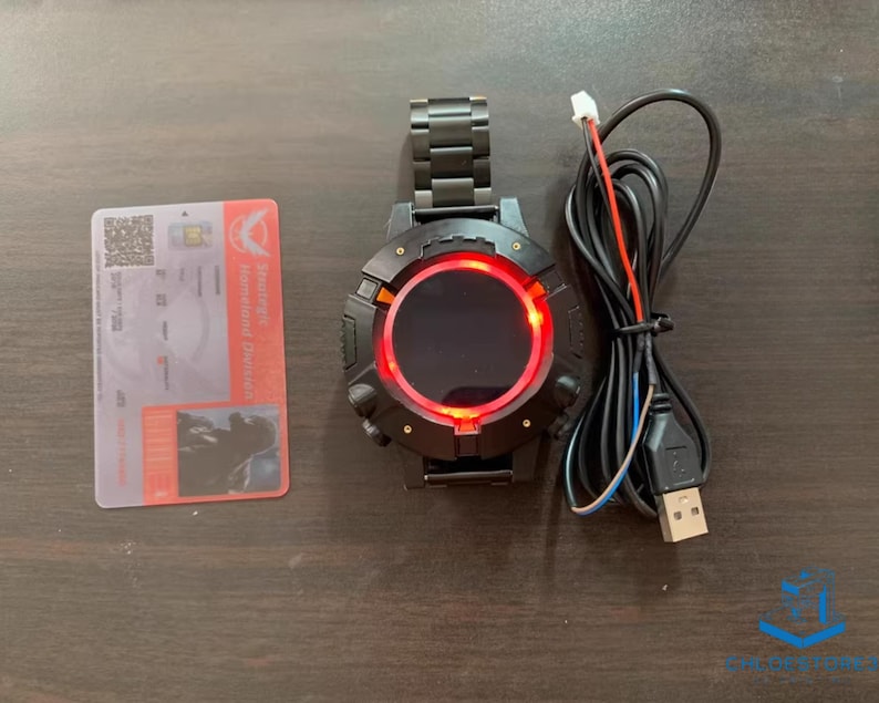 May include: A black smartwatch with a red digital display and a USB charging cable. The watch has a metal band and a round face.
