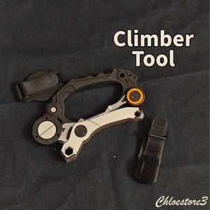 Puede incluir: Una herramienta de escalada negra y plateada con un acento naranja. La herramienta tiene un dise&ntilde;o tipo mosquet&oacute;n con una correa y el texto "Climber Tool". La herramienta est&aacute; sobre un fondo oscuro.
