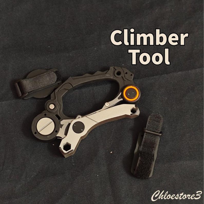 Puede incluir: Una herramienta de escalada negra y plateada con un acento naranja. La herramienta tiene un dise&ntilde;o tipo mosquet&oacute;n con una correa y el texto "Climber Tool". La herramienta est&aacute; sobre un fondo oscuro.