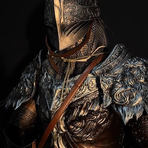 May include: A detailed, metallic knight's armor set. The helmet features intricate patterns and a visor. The chest and shoulder pieces are adorned with ornate designs. A brown leather strap crosses the chest. The armor has a silver and bronze color scheme.