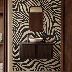 Pode incluir: Uma parede coberta com papel de parede de listras de zebra em preto e bege, com um móvel de banheiro flutuante marrom escuro, um espelho retangular de cantos arredondados e uma cuba de pedra branca salpicada com torneira prateada.