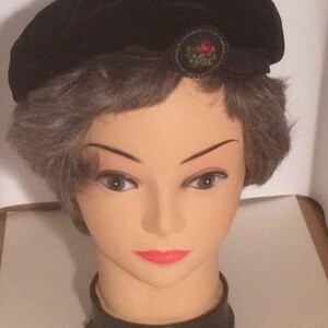 Black velvet beret with needlework pin