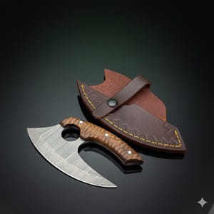 Op de afbeelding: Een kleine, gebogen bijl met een stalen lemmet met patroon en een houten handvat. Het wordt gepresenteerd met een bruine leren schede met gele stiksels en een drukknoopsluiting. Het ontwerp is rustiek en functioneel.