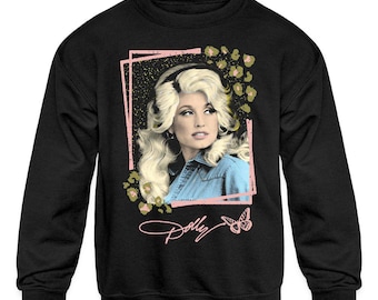 Op de afbeelding: Zwarte sweatshirt met een portret van een vrouw met blond haar en een spijkerblouse. De afbeelding bevat een roze kader, luipaardprint accenten en de naam "Dolly" in script met een vlinder.