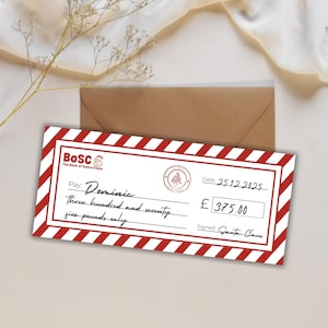 May include: A novelty Christmas check from the Bank of Santa Claus, featuring a red and white striped border. The check is made out to "Dominic" for £375.00, dated December 25, 2025, and signed by Santa Claus. A brown envelope is in the background.
