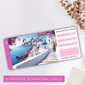 以下が含まれることがあります： 「YOU'RE GOING TO Santorini」の文字とサントリーニ島のイラストが描かれた、ピンクと白の搭乗券。「SURPRISE BOARDING PASS」の文字が下部にあります。搭乗券には、乗客、出発、帰着、メッセージの欄があります。