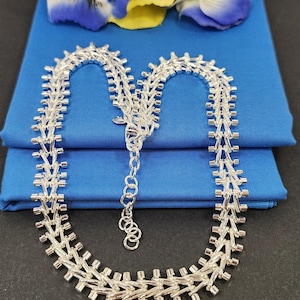 May include: A silver chain necklace with a delicate, intricate design. The chain is made of small, linked squares and is about 18 inches long.