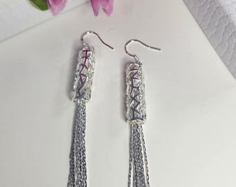 May include: Silver dangle earrings with a geometric design and a tassel of silver chains.