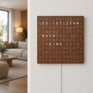 Könnte beinhalten: Eine quadratische Wanduhr mit rostiger Metalloberfläche und einem Buchstabenraster. Der beleuchtete weiße Text zeigt die Uhrzeit ES IST ZEHN NACH EINS an. Ein weißes Stromkabel führt von der Unterseite der Uhr nach unten.